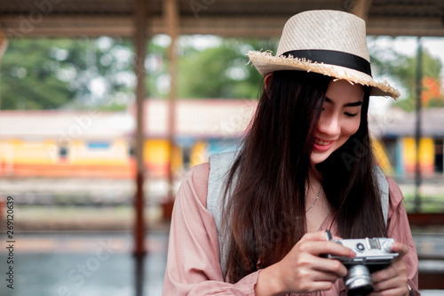 Smiling woman traveler with backpack holding vintage camera on holiday relaxation at the train station,relaxation concept, travel concept