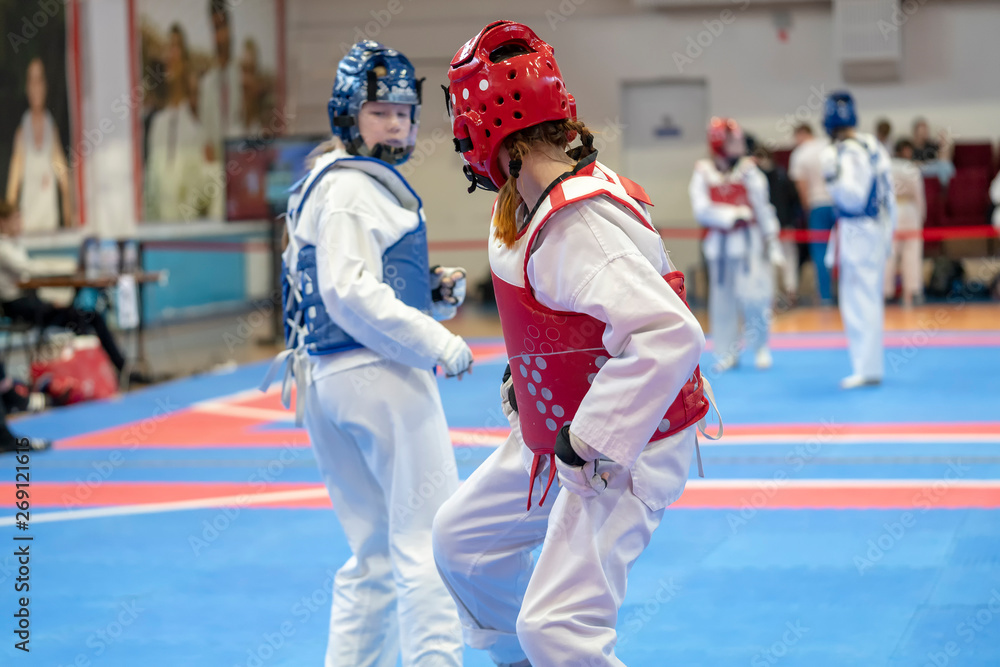 Obraz premium two girls in blue and red Taekwondo equipment are fighting at doyang