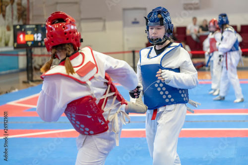 two girls in blue and red Taekwondo equipment are fighting at doyang