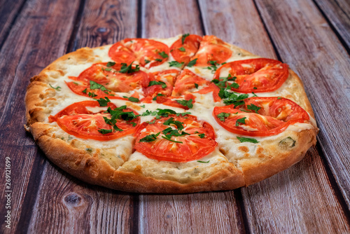pizza with tomatoes is on a wooden table