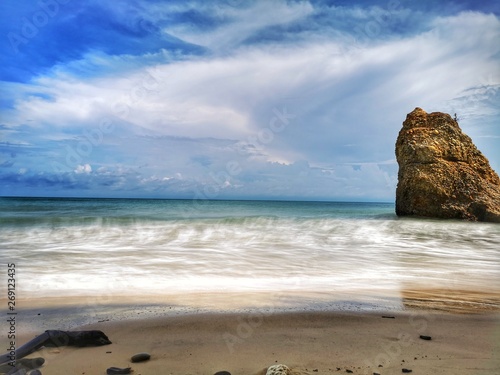 Beautiful single rock formation on the seashore with silky smooth water reflection background. © Josephine Julian