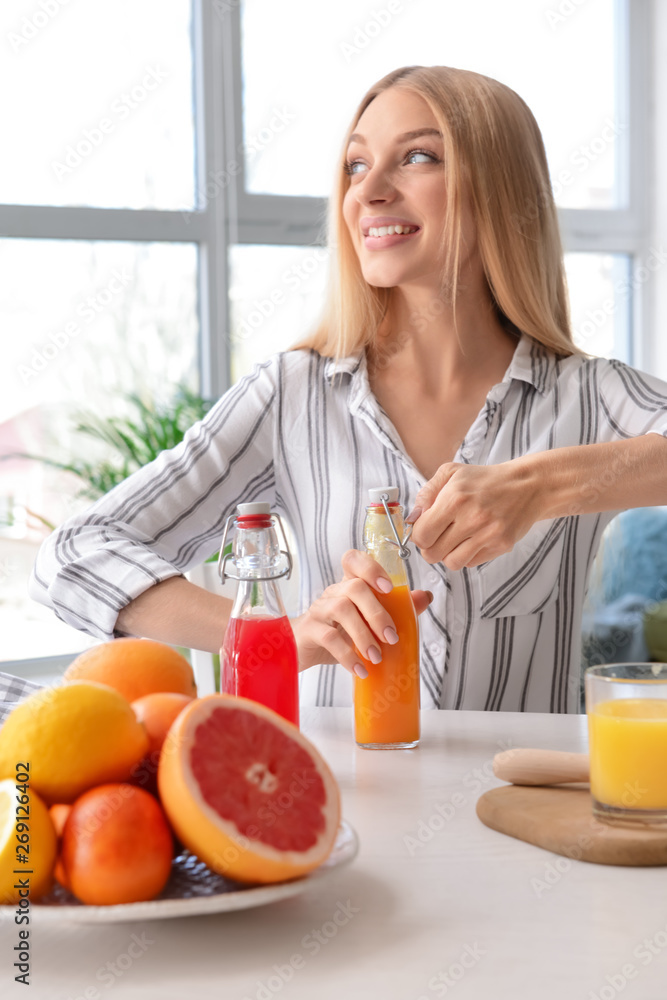 Beautiful young woman with bottles of fresh juice at home Beautiful young woman with bottles of fresh juice at home