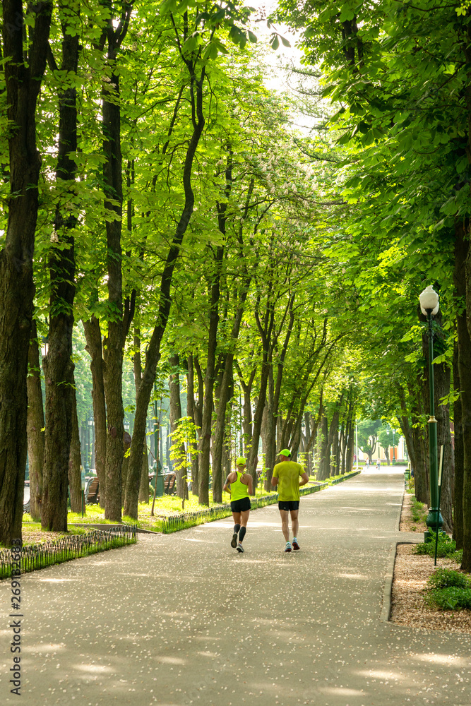 A man and a woman in sportswear doing a morning jog in the park in spring or summer.  Healthy active lifestyle.  Health care.
