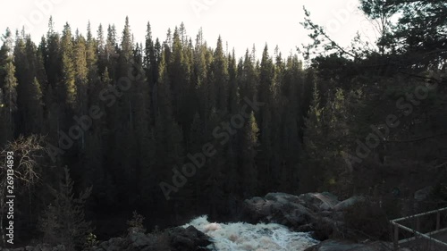 Aerial, static, drone shot over Hepokongas waterfall, revealing pine forests and wilderness of Puolanka area, on a sunny spring day, in Kainuu, Finland photo