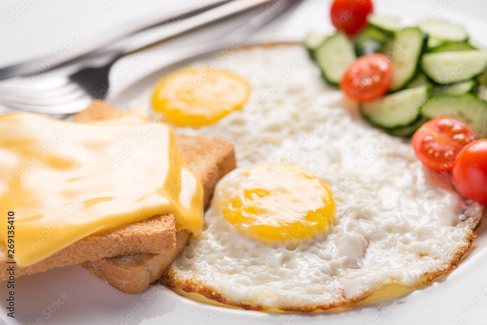 Plate of fried eggs and fresh vegetables, cheese toast