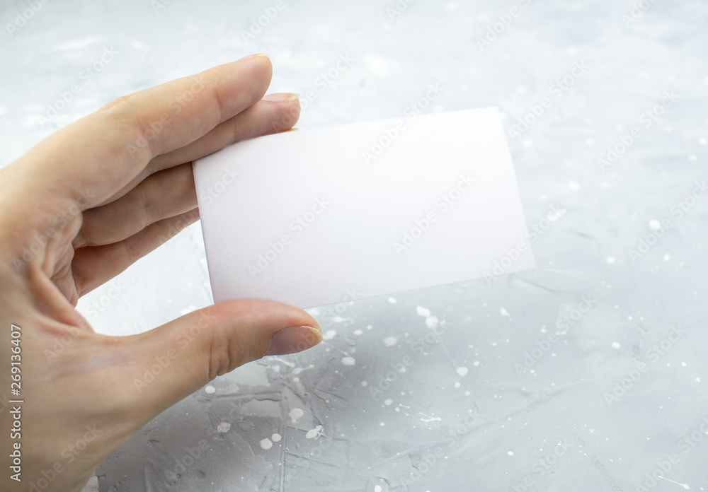 ockup of a business cards placed horizontal on a gray background. Hand holding white card on grunge background, concrete. Top of view. ockup of a business cards placed horizontal on a gray background. Hand holding white card on grunge background, concrete. Top of view.
