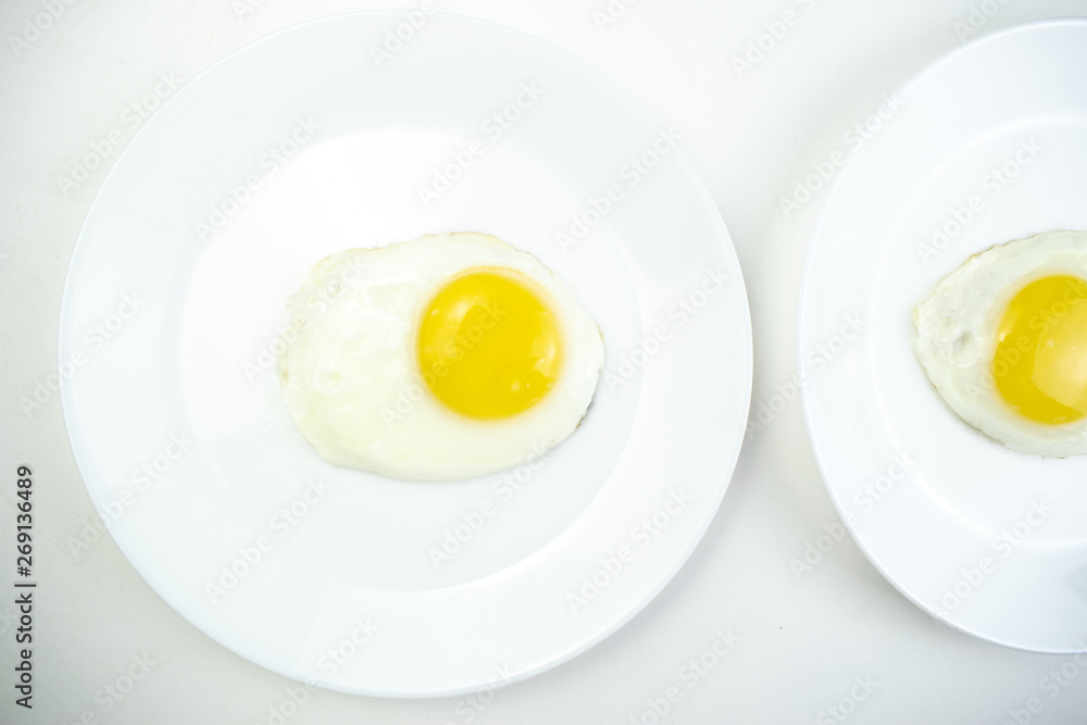traditional breakfast of two fried eggs. White plate with eggs on the background of a white wooden table. Concept image of breakfast, healthy eating. traditional breakfast of two fried eggs. White plate with eggs on the background of a white wooden table. Concept image of breakfast, healthy eating.