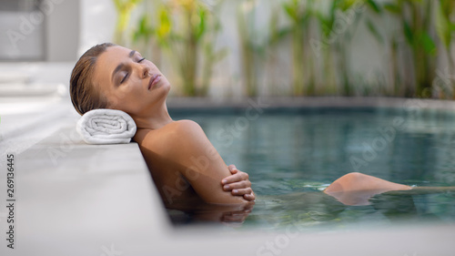 Young beautiful girl relaxes in the pool during spa procedures