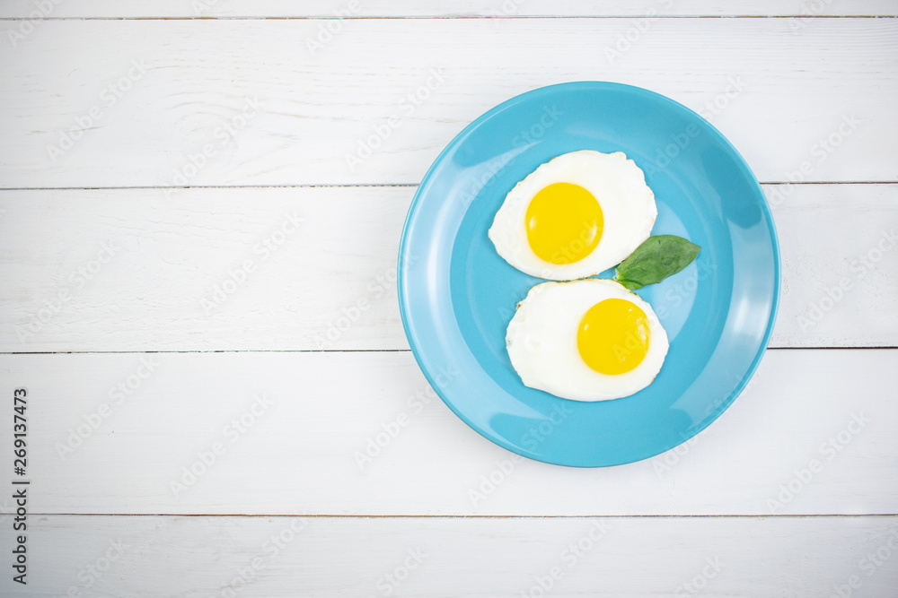 Plate with tasty oatmeal and banana slices and fried eggs on white wood background. Concept image of breakfast, healthy eating. Plate with tasty oatmeal and banana slices and fried eggs on white wood background. Concept image of breakfast, healthy eating.
