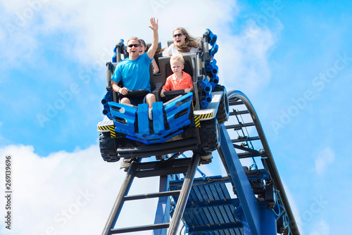 Photo Young family having fun riding a rollercoaster at a theme park