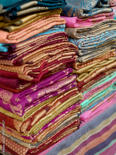 View of Indian woman dress sarees or saris rolled and stacked in display of shop