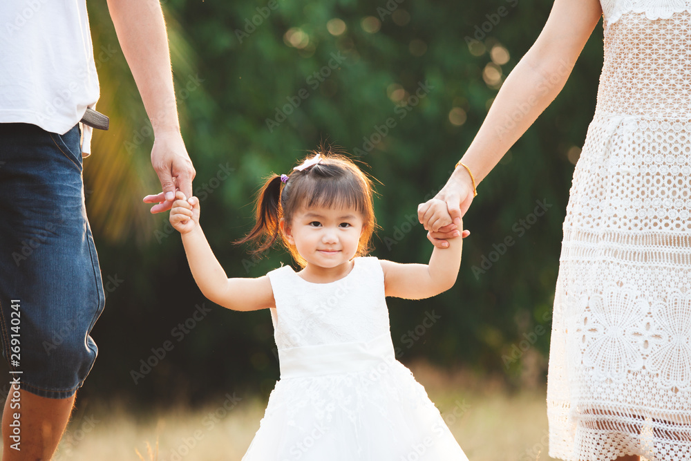 Φωτογραφία Cute asian little girl holding hand and walking with her parents in the park wit
