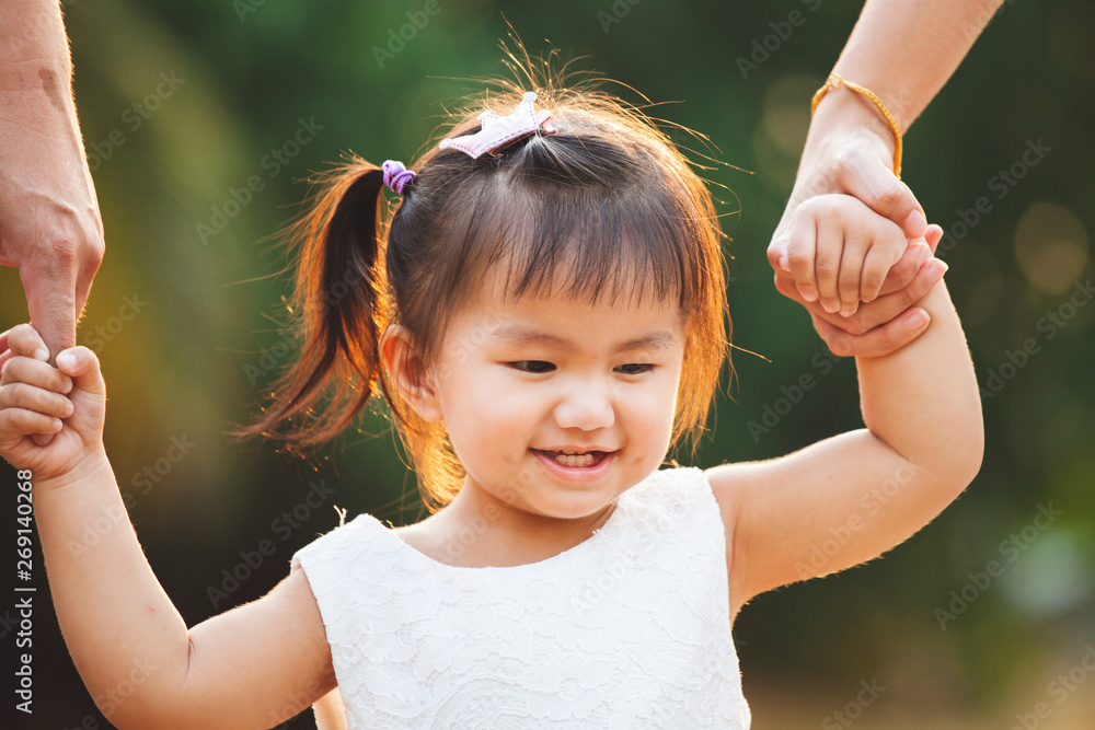Φωτογραφία Cute asian little girl holding hand and walking with her parents in the park wit