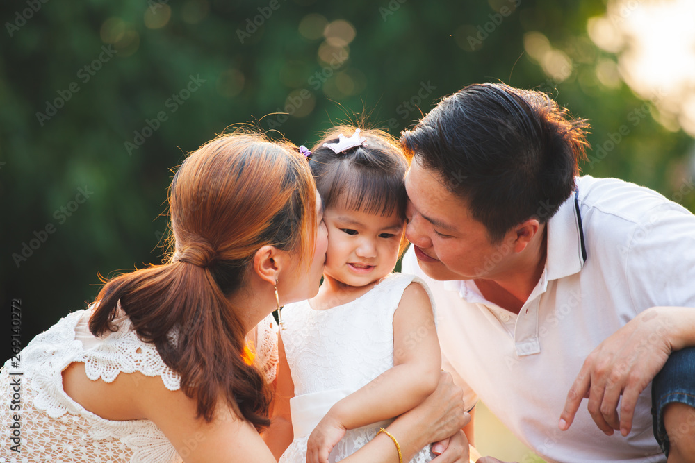 Φωτογραφία Asian family father and mother kissing daughter and playing together in the park