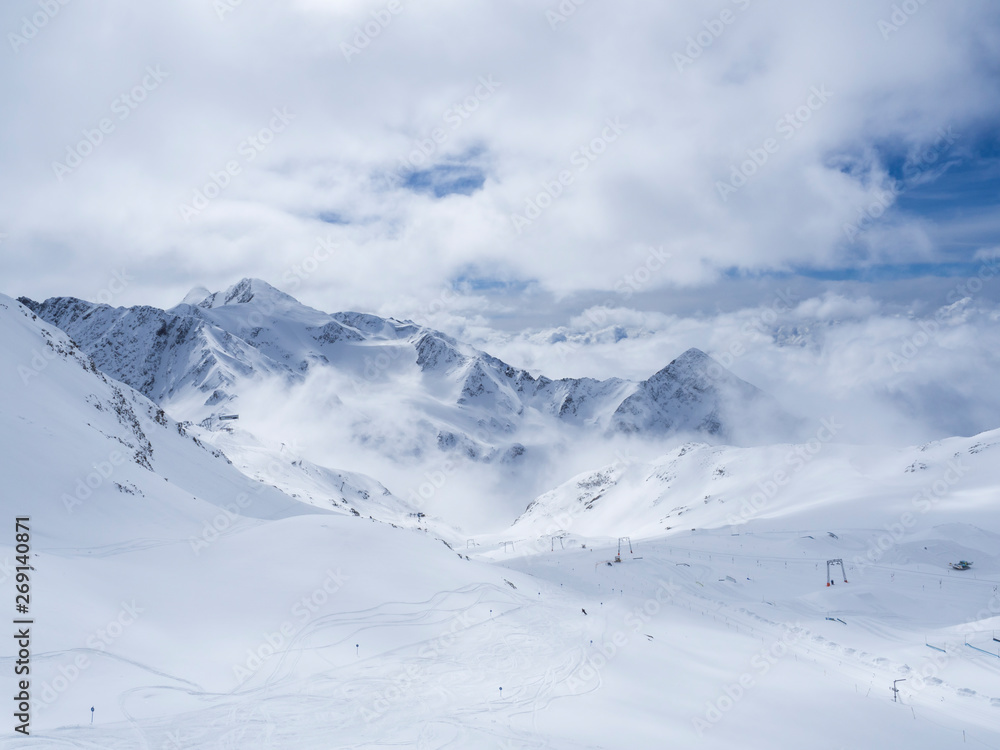 Winter landscape with snow covered mountain slopes and empty pistes, spring sunny day at ski resort Stubai Gletscher, Stubaital, Tyrol, Austrian Alps.