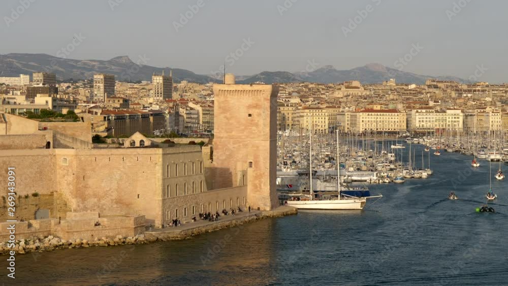 Marseille, France. Boats sailing by the Old Port of Marseille. A tower of Fort Saint-Jean is seen in this shot. The Fort was built by Louis IV in 1660 at the former site of Order of the Knights Marseille, France. Boats sailing by the Old Port of Marseille. A tower of Fort Saint-Jean is seen in this shot. The Fort was built by Louis IV in 1660 at the former site of Order of the Knights