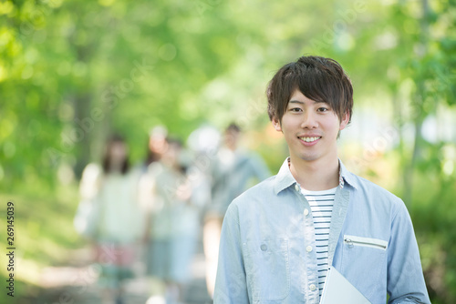 新緑の中で微笑む大学生