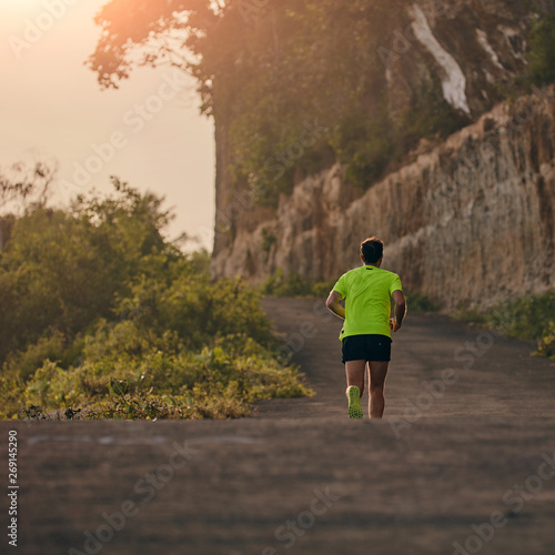 Man jogging on a downhill / uphill in suburb mountain road.