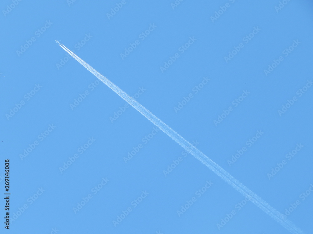 In the blue sky, a white trail from the plane and the plane itself, which seems to be a toy In the blue sky, a white trail from the plane and the plane itself, which seems to be a toy