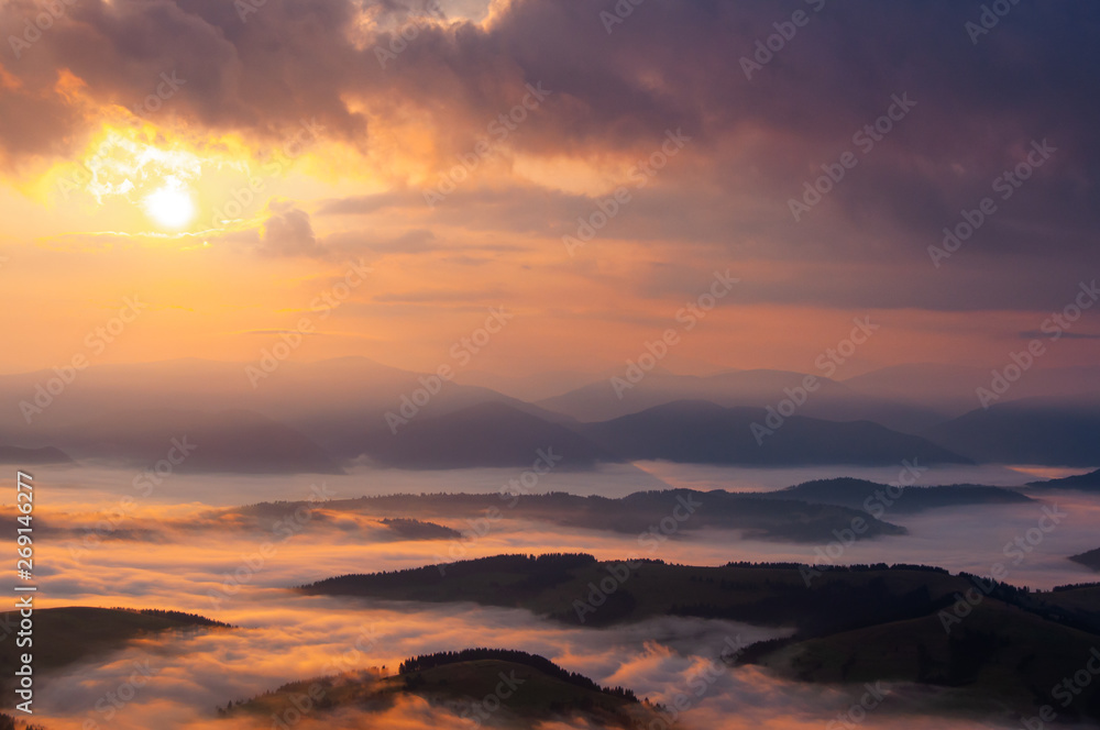 Misty sunrise in Carpathian mountains, clouds and fog in the dusk