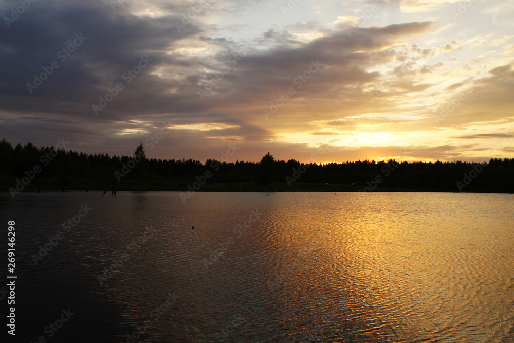Bright sunset on a forest lake. Silence in the evening.