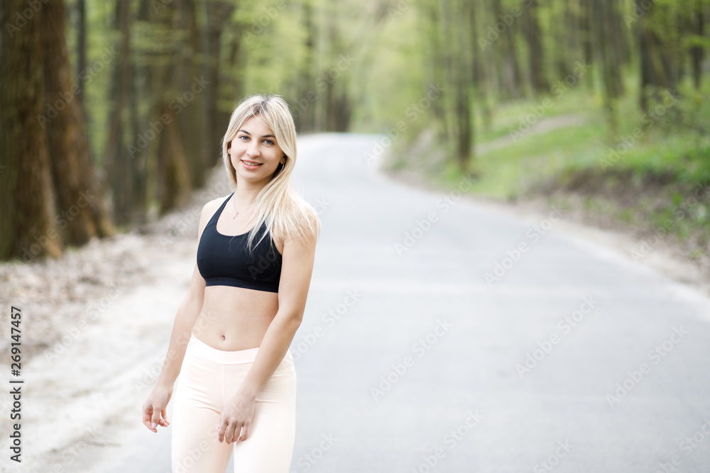 A young, sympathetic blond woman is actively spending time outdoors. The girl is dressed in sportswear. Exercise Outdoors. Health and benefits for the body A young, sympathetic blond woman is actively spending time outdoors. The girl is dressed in sportswear. Exercise Outdoors. Health and benefits for the body