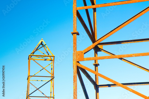 Schilderij op canvas Old rusty iron structure with bolted metal profiles against a blue sky