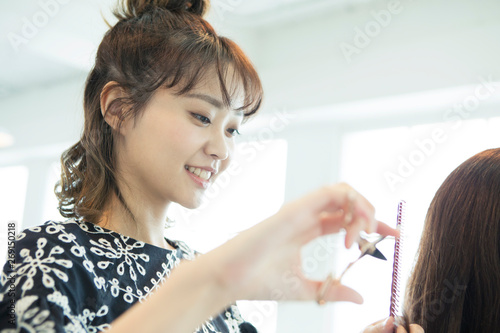 女性の髪の毛を切る女性美容師