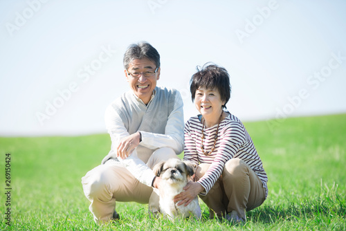 Papier peint 草原で微笑むシニア夫婦と犬