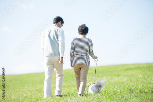 草原で犬の散歩をするシニア夫婦の後姿 photo