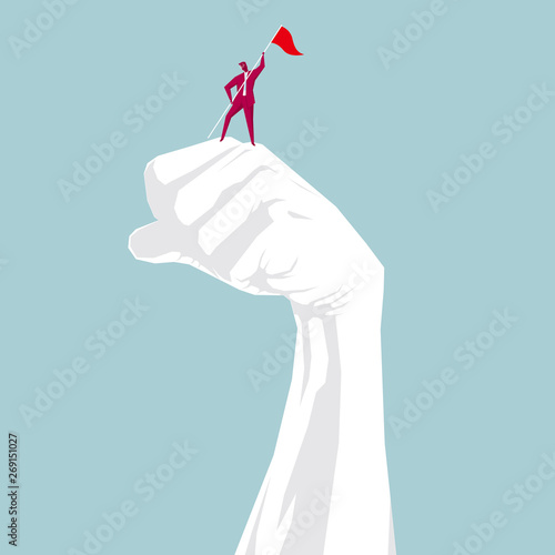 The businessman occupied the top of the fist. Isolated on blue background.