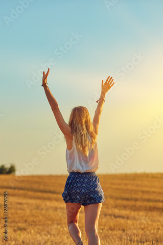 Cute young woman jumping in a wheat field. © astrosystem