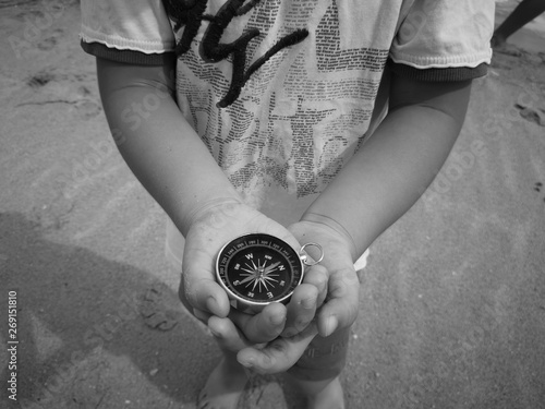 A little boy holding a compass is an instrument used for navigation and orientation that shows direction relative to the geographic cardinal directions.