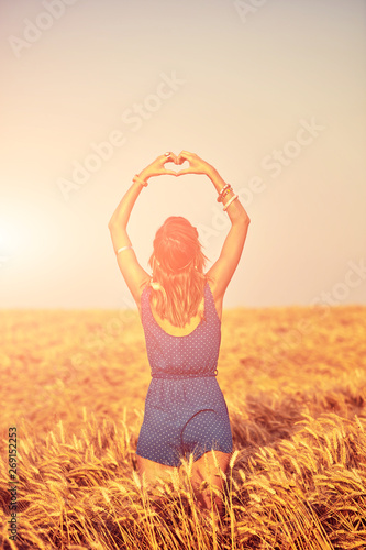 Fototapeta Naklejka Na Ścianę i Meble -  Girl holding heart-shape symbol for love in a wheat field.