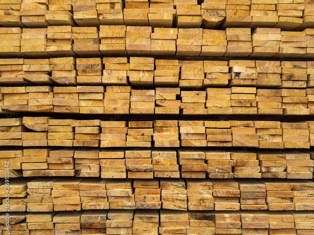 Lots of planks stacked on top of each other in the warehouse. Lumber for further use in construction Lots of planks stacked on top of each other in the warehouse. Lumber for further use in construction
