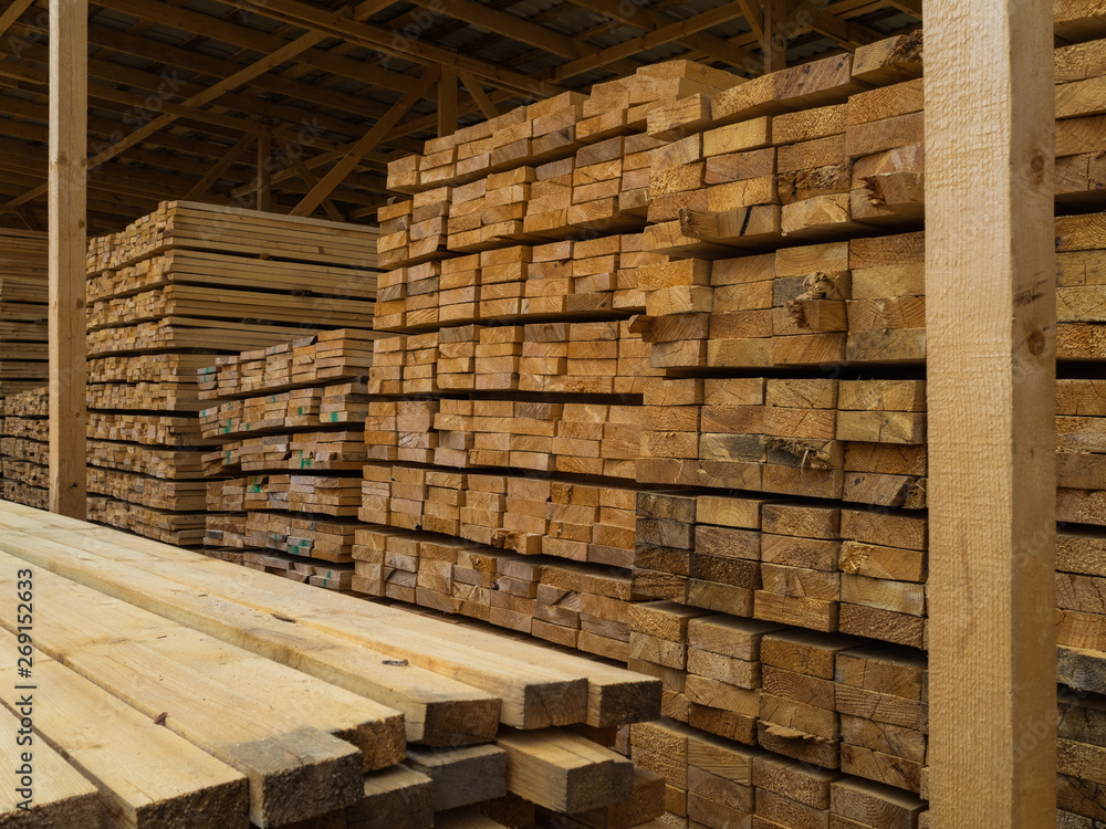 Lots of planks stacked on top of each other in the warehouse. Lumber for further use in construction Lots of planks stacked on top of each other in the warehouse. Lumber for further use in construction