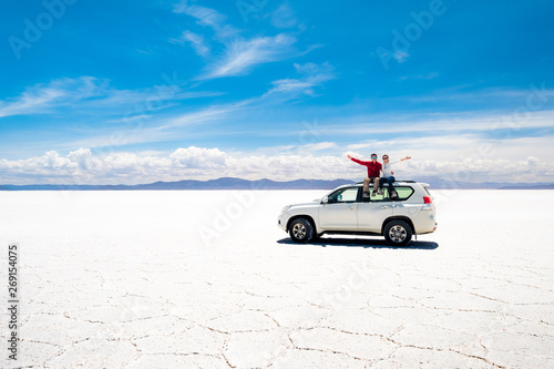Foto Tourists on white car rooftop in spacious sunshine Salar de Uyuni