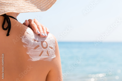 Sunscreen lotion in sun shape on tanned woman's shoulder photo