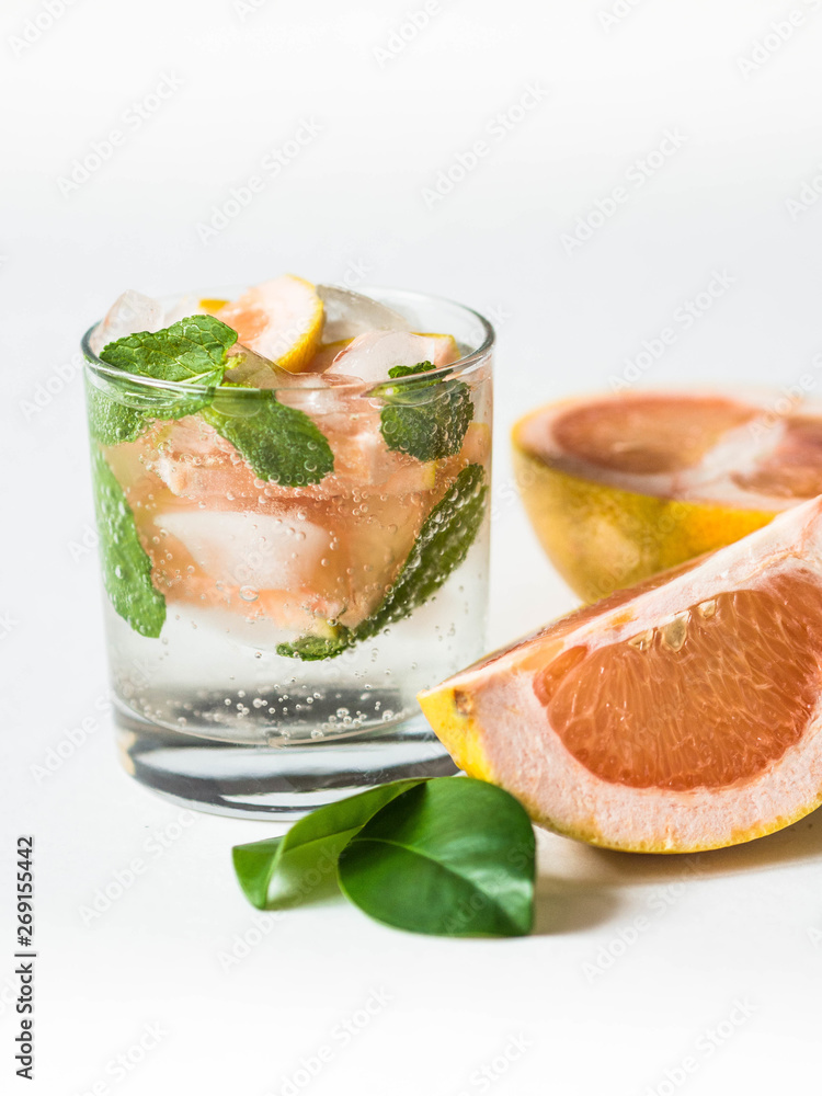 Cocktail or lemonade with mint and grapefruit in glass. Fruit lemonade. White background. Healthy citrus summer drink.