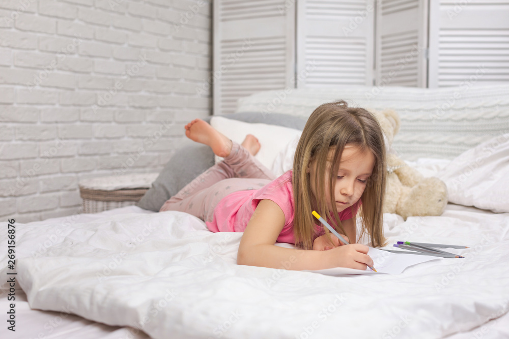cute little girl drawing pictures while lying on bed. Kid painting at home cute little girl drawing pictures while lying on bed. Kid painting at home