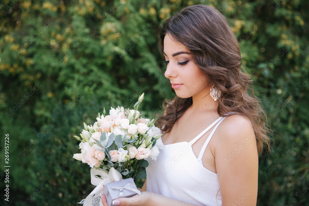 Gorgeous female in white dress slime. Beautiful girl hold a bouquet of flowers in hands Gorgeous female in white dress slime. Beautiful girl hold a bouquet of flowers in hands
