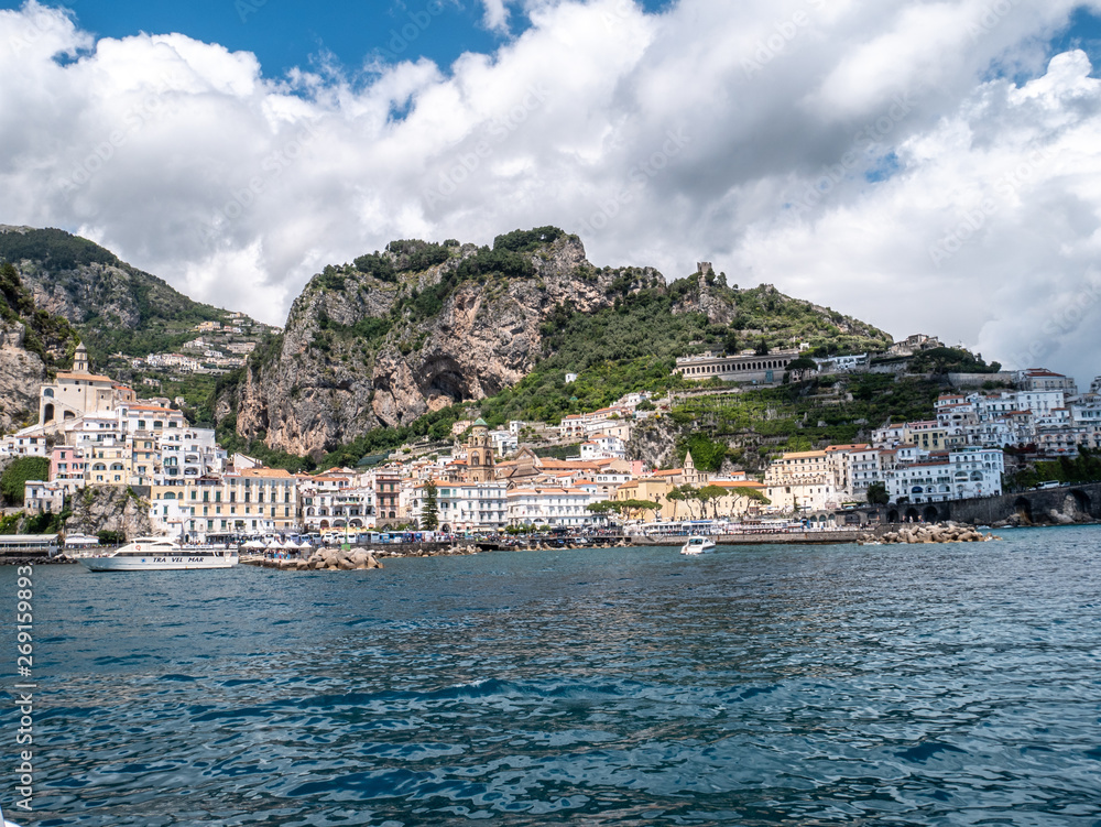 Positano, Salerno, Campania, Italy, Europe: view of Amalfi from the sea on a boat entering the port on the Amalfi Coast. Wake of a ship with a marine village in the background