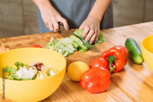 Woman hands cutting chopping lettuce leaves. Organic fresh veggies for healthy balanced vegetarian salad recipe. Dieting.