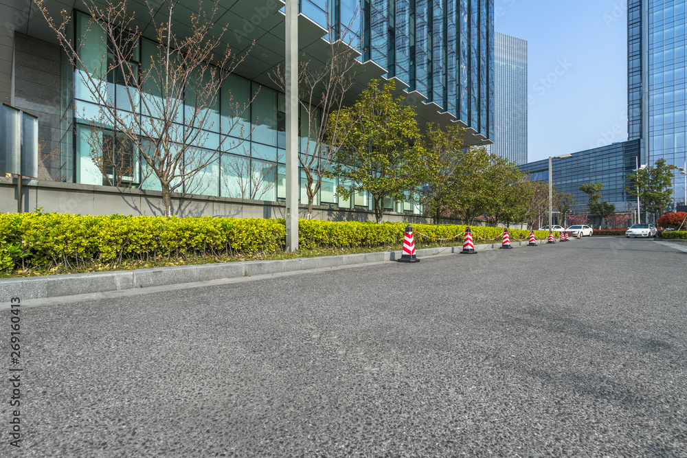 Naklejka premium empty asphalt road near glass office building.