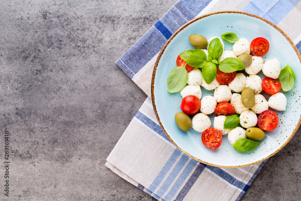 Delicious caprese salad with ripe cherry tomatoes and mini mozzarella cheese balls with fresh basil leaves.