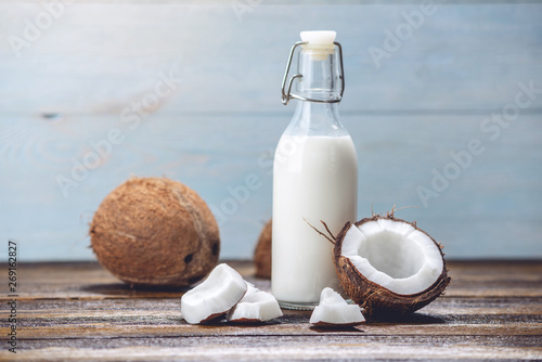 Coconut milk in a bottle with white flesh on a wooden background. Organic healthy product used in cosmetology