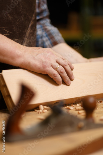 Carpenter working with wood parts and planer on the workbench