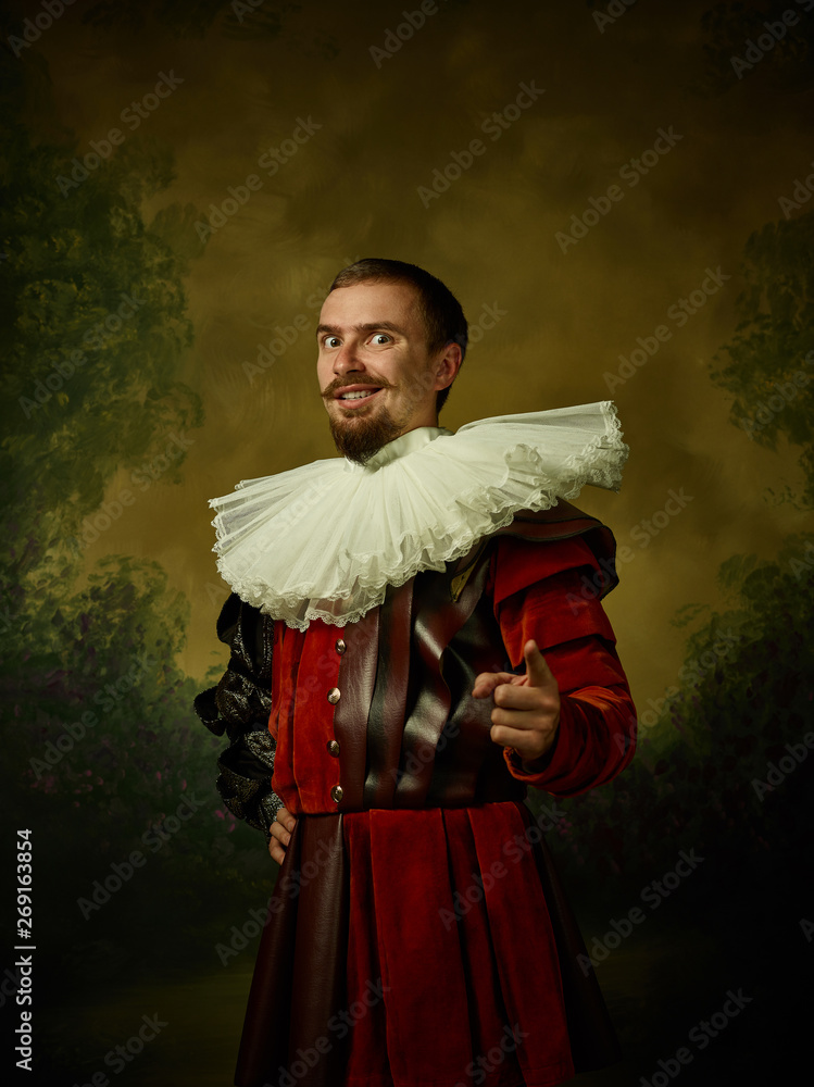 Young man as a medieval knight on dark studio background. Portrait in ...