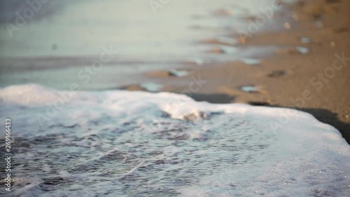 footprints in the sand being covered by sea wave // handheld photo