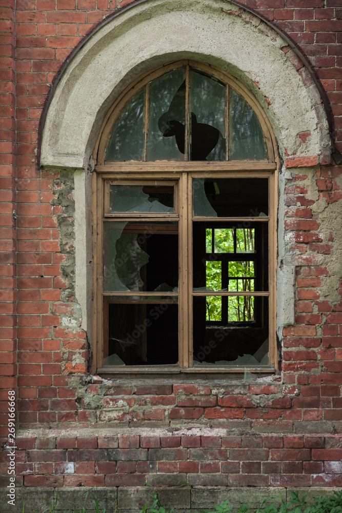 Obraz premium broken window in an abandoned house, broken glass, red brick, forgotten residence